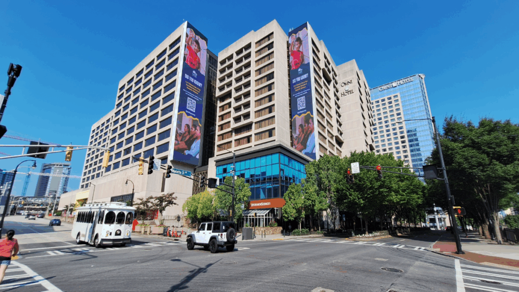 The Center (former CNN Center) under renovation, with cranes, digital billboards, and new public plazas in vibrant downtown Atlanta