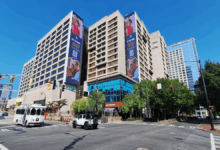 The Center (former CNN Center) under renovation, with cranes, digital billboards, and new public plazas in vibrant downtown Atlanta