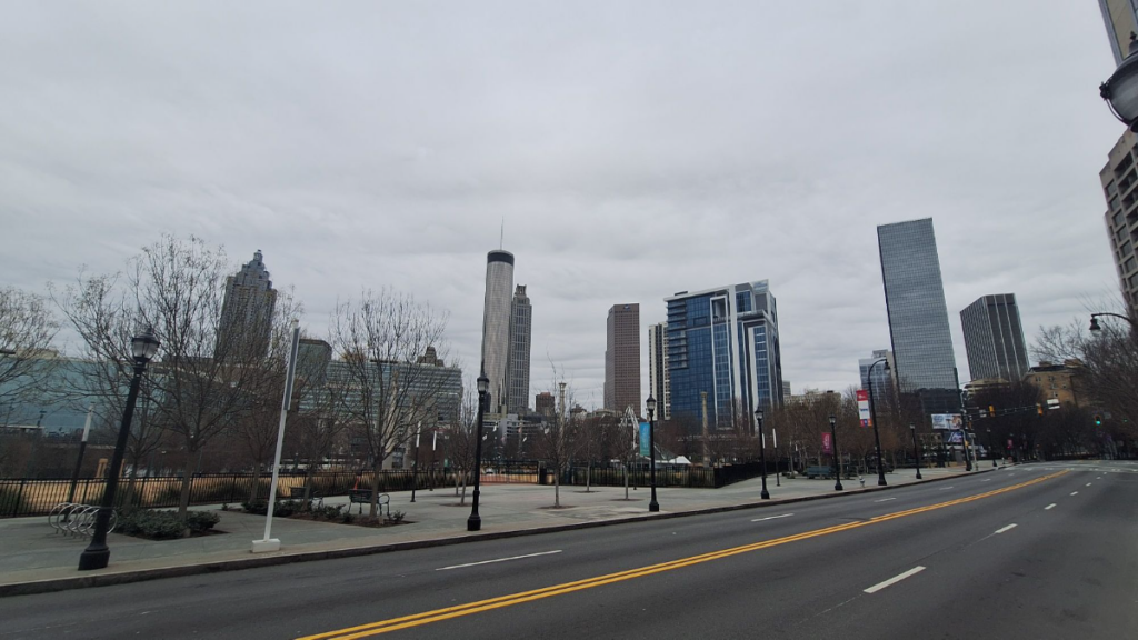 Empty Atlanta skyline under gray winter storm clouds, featuring Bank of America, Truist, and AT&T skyscrapers with bare trees lining a deserted street and sidewalk on January 26, 2026—evoking the quiet isolation of MARTA's bus suspension.