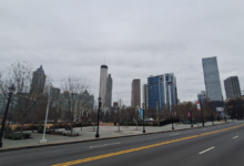 Empty Atlanta skyline under gray winter storm clouds, featuring Bank of America, Truist, and AT&T skyscrapers with bare trees lining a deserted street and sidewalk on January 26, 2026—evoking the quiet isolation of MARTA's bus suspension.