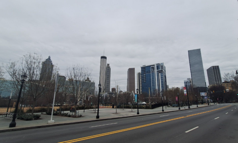Empty Atlanta skyline under gray winter storm clouds, featuring Bank of America, Truist, and AT&T skyscrapers with bare trees lining a deserted street and sidewalk on January 26, 2026—evoking the quiet isolation of MARTA's bus suspension.